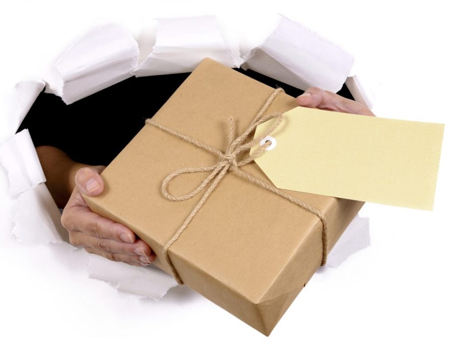 Foto von zwei Händen, die ein Geschenkpäckchen durch ein Papierloch halten